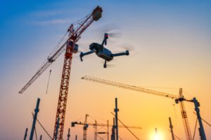 Images aériennes capturées par drone montrant un coucher de soleil avec une grue de construction en silhouette.